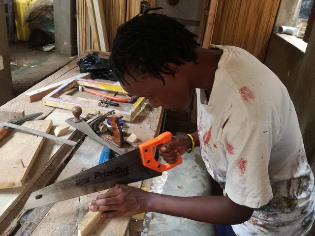 Carpenter cutting a timber board with a handsaw
