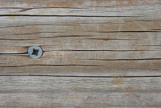 Weathered grey timber boards with a screw head